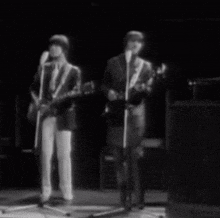 two men are singing and playing guitars on a stage .