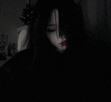 a girl with long black hair is covering her face with her hair in a dark room .