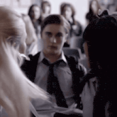 a man in a tie talks to a girl in a crowded room