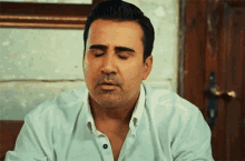 a man in a white shirt is making a funny face with his eyes closed