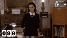 a woman in a black sweater and plaid skirt stands in front of a fireplace with the number 099 on the bottom