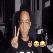 a young boy is making a peace sign with his hands .