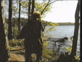 a person standing in the woods near a body of water