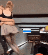 a man and a woman are dancing in a bowling alley with a sign that says ' bowling ' on it