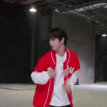 a young man in a red baseball uniform is dancing in a warehouse .