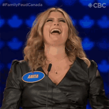 a woman with a name tag that says anita is laughing in front of a microphone