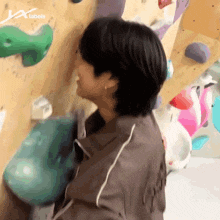 a man is climbing a climbing wall with a x labels logo in the corner