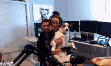 a man and a woman are holding a dog in a room