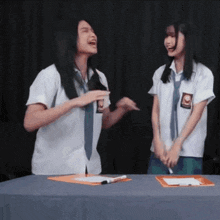 two girls in school uniforms are laughing together