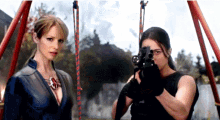 two women are standing next to each other holding guns