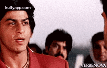 a man in a red shirt is standing in front of a crowd of people and making a funny face .