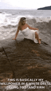 a woman in a white dress is sitting on a rock in the water .