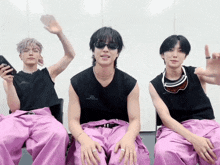 a man wearing sunglasses and a shirt that says ' seoul ' on it sits with two other men
