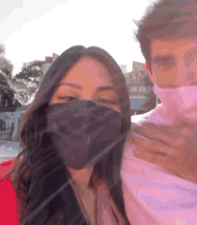 a woman wearing a face mask is standing next to a man wearing a face mask