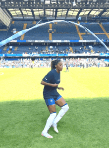 a female soccer player is jumping a rope on a field in front of an empty stadium