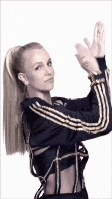 a woman wearing a black jacket with gold stripes is dancing