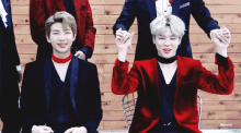 two men in red jackets are holding hands in front of a group of men
