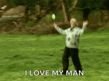 a man is holding a badminton racket in a field and says " i love my man "