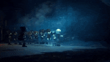 a group of people are standing in a dark room with a light coming out of the ceiling