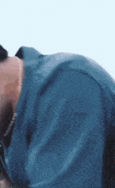 a man wearing a blue shirt and a necklace is laying on his back .