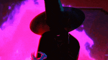 a person in a witch hat is standing in front of a purple background