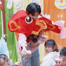 a boy in a fish costume holds a stuffed animal