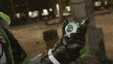 a person wearing a black and green glove holds a green object with a green eye