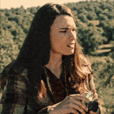 a woman in a plaid jacket holds a camera in her hands