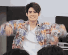 a young man wearing a plaid shirt is dancing in front of a crowd .