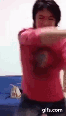 a man in a red shirt is dancing with his arms outstretched