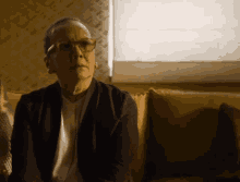 an older woman wearing glasses is sitting on a yellow couch