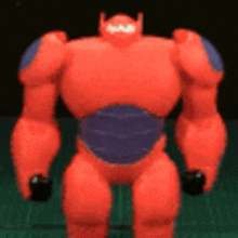 a toy robot from big hero 6 is standing on a cutting board .