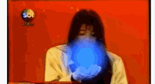 a woman is holding a blue ball in her hands in front of a sign that says sbt .