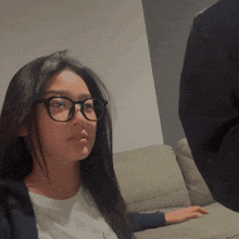 a woman wearing glasses is sitting on a couch with a t-shirt that says i love you