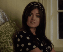 a woman wearing a black and white polka dot shirt is sitting on a couch