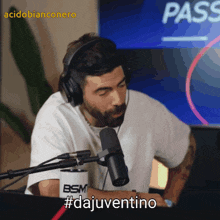 a man wearing headphones sits in front of a microphone with the hashtag #dajuventino on the screen