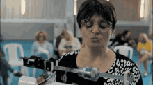 a woman wearing glasses and a leopard print shirt weighs herself on a machine