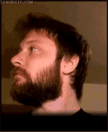 a man with a beard is looking up at something in the distance