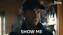 a man in a hat says show me in front of the boys logo