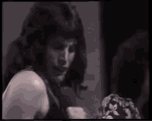 a man with long hair is standing in front of a mirror in a dark room .