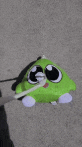 a green stuffed animal is laying on the ground covered in white foam .