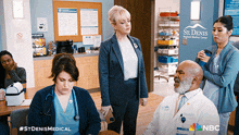 a group of doctors and nurses standing in a room with a sign that says st denis regional medical center