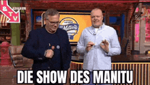 two men are standing next to each other in front of a television .