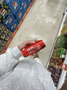 a person is holding a can of hang soda in a store