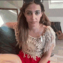 a woman is sitting on a couch wearing sunglasses and a red dress .