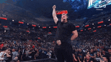 a man in a black shirt stands in front of a crowd at a raw event