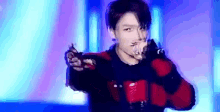 a young man is holding a microphone in his hand and singing into it on a stage .