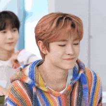 a young man wearing a colorful striped sweater is smiling
