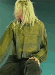 a woman with long blonde hair is wearing a green shirt
