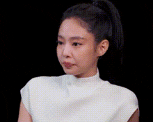 a close up of a woman 's face with a ponytail and a white shirt .